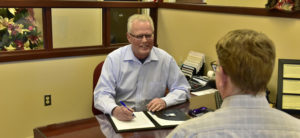Peoples Bank & Trust Employee sitting at desk talking to customer