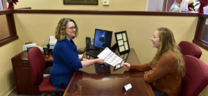 Peoples Bank & Trust employee handing document to customer